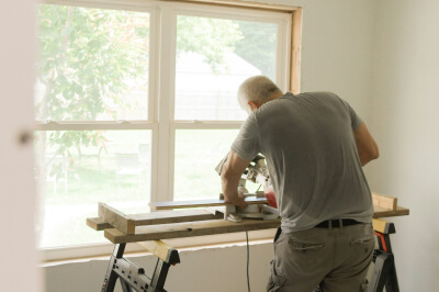 Image of a man using a saw while doing a home improvement project.